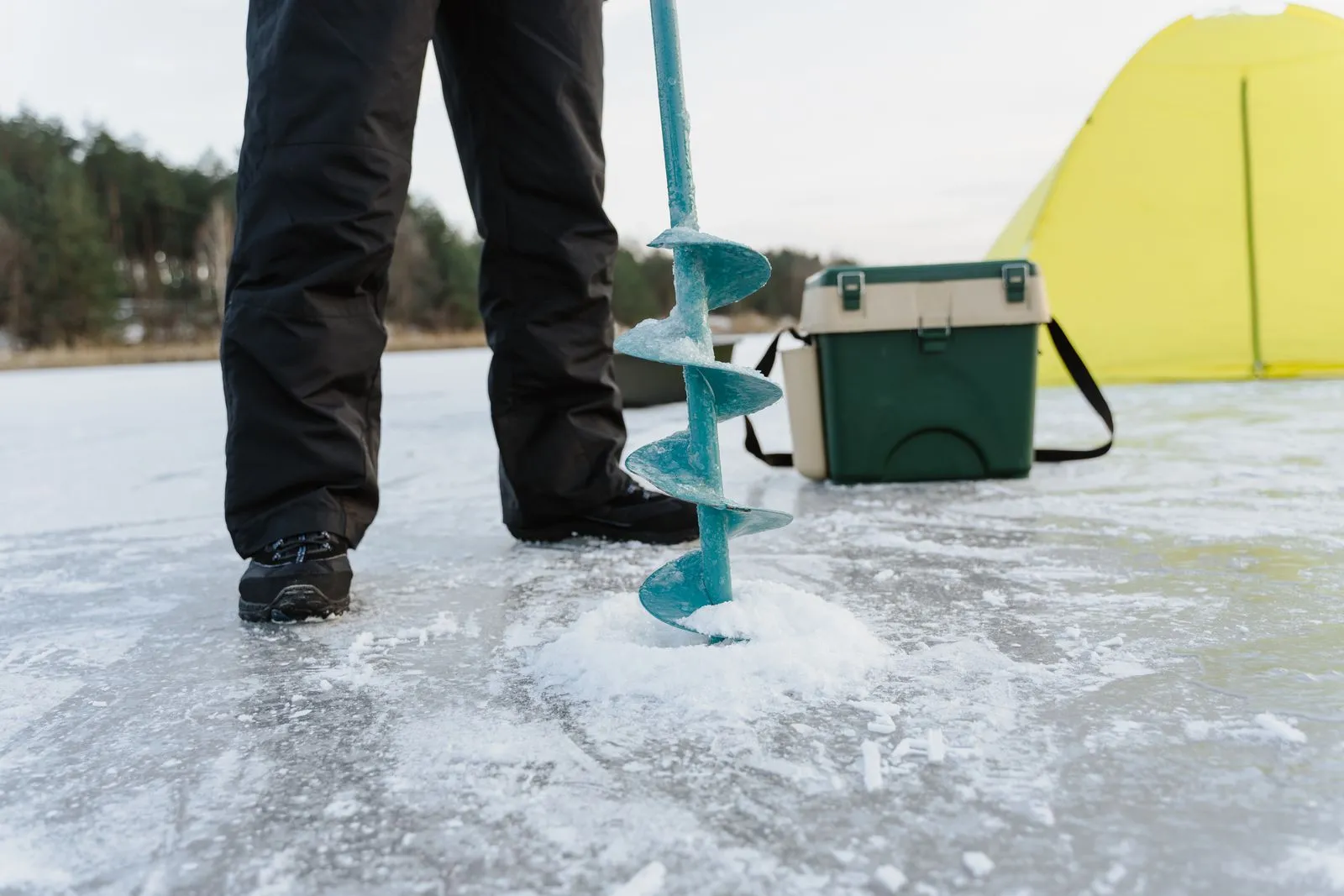 氷に穴を開ける道具のそばに置かれた緑色の保冷ボックス