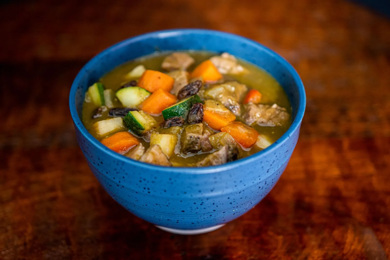 青いボウルに盛られた野菜と肉の煮込み