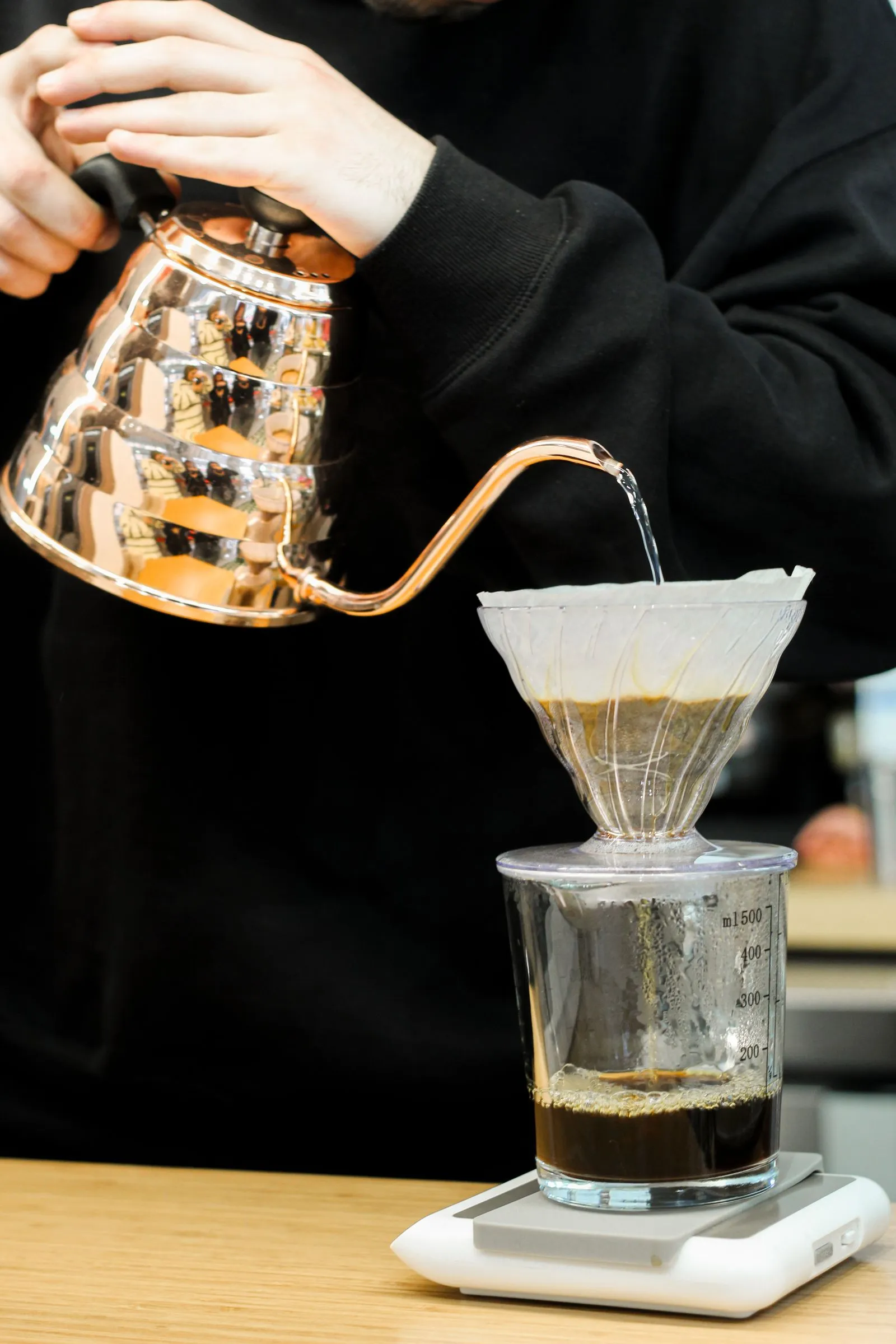 銅色の細口ケトルから、コーヒードリッパーのフィルターへお湯が注がれている