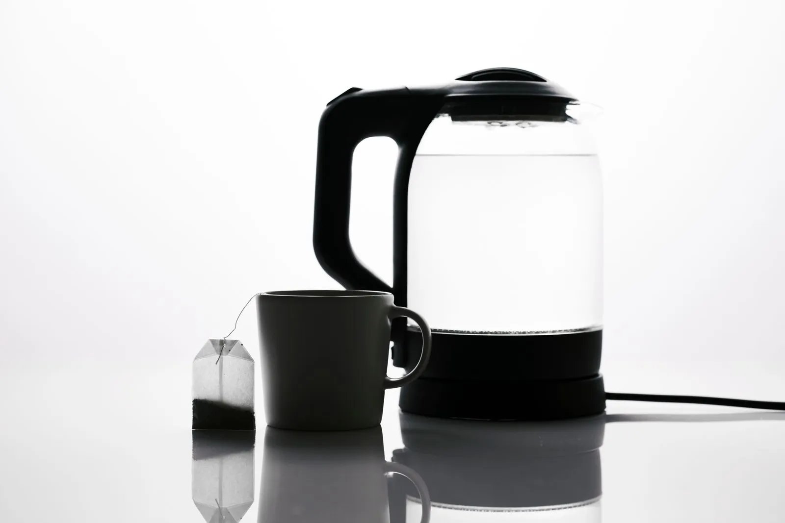 ティーバッグとマグカップの横に置かれたガラス製の電気ケトル