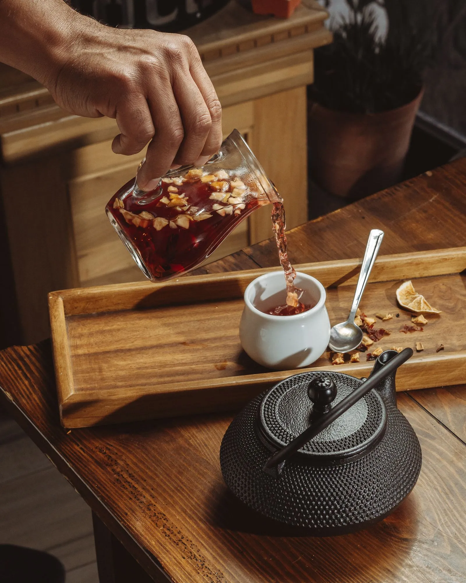 木製トレーの上で果実茶をカップへ注ぐ手元