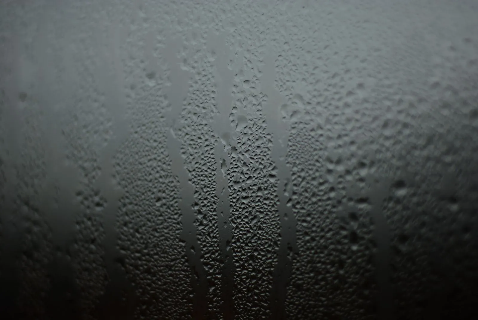ガラス窓の表面に無数の水滴が付き、筋になって流れ落ちている