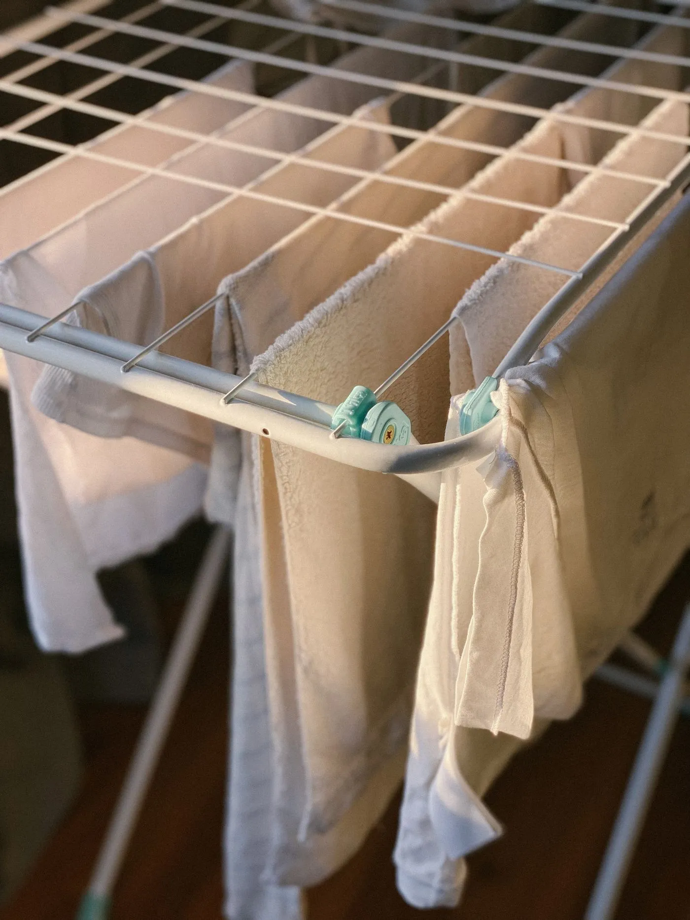 折りたたみ式の物干しラックに掛けられた白い洗濯物