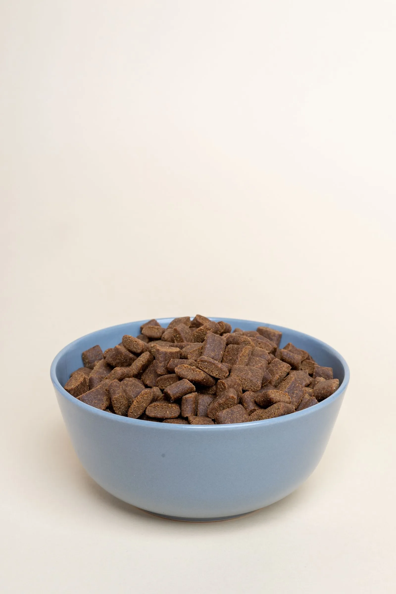 青みがかった陶器のボウルに山盛りになった、茶色いフード