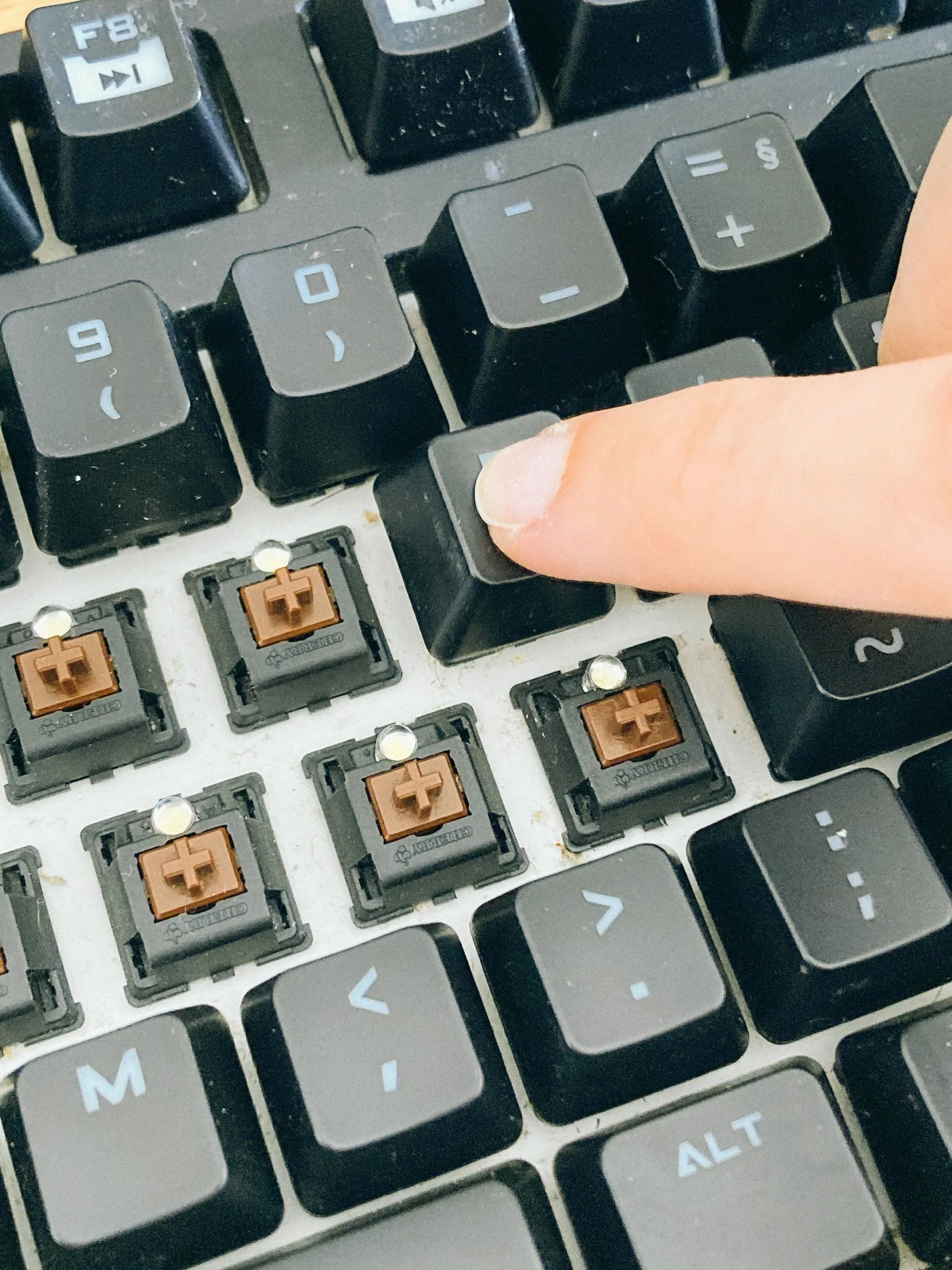 ほこりの積もったキーボードで、指がキーキャップを押し込んでいる