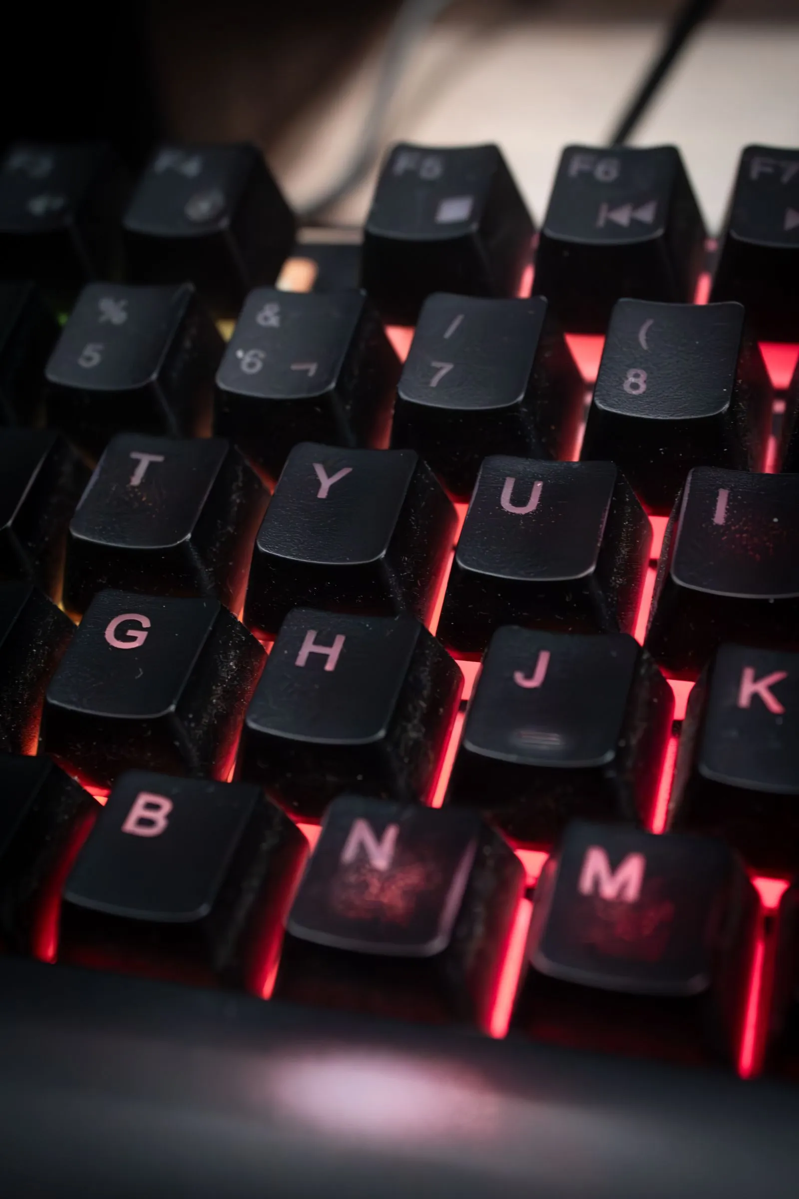 赤い光に照らされたキーボードのキーに、細かいほこりが付着している