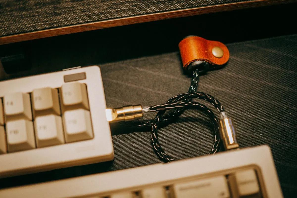 白いキーボードが2台、編み込みケーブルで革の留め具とつながれている