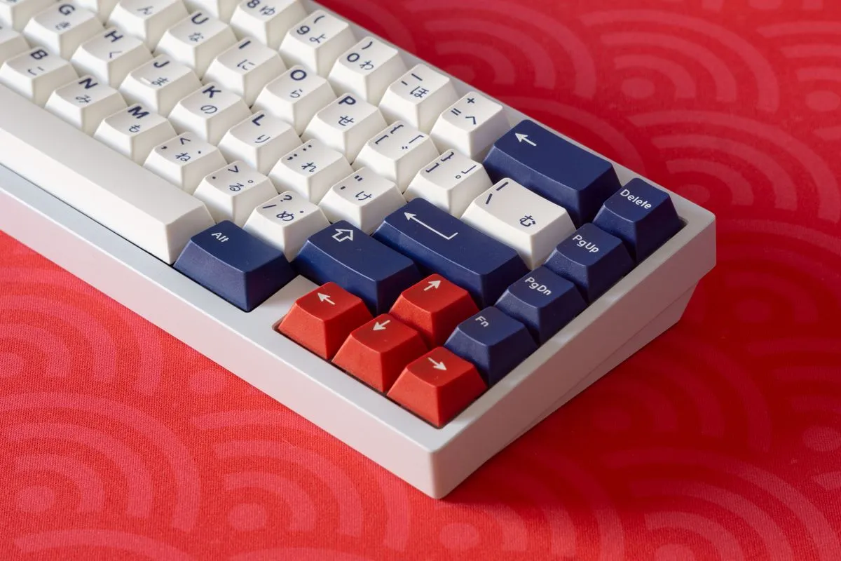 赤と白のキーキャップが並ぶキーボードの角に、青い矢印キーとひらがなの刻印が見える