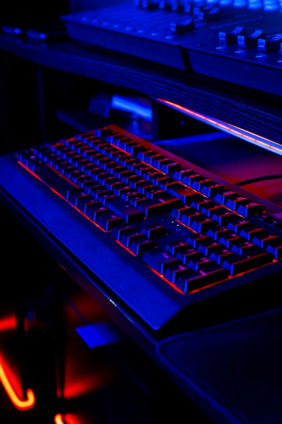 暗い部屋で、虹色に光るキーボードに向かって手を伸ばしている