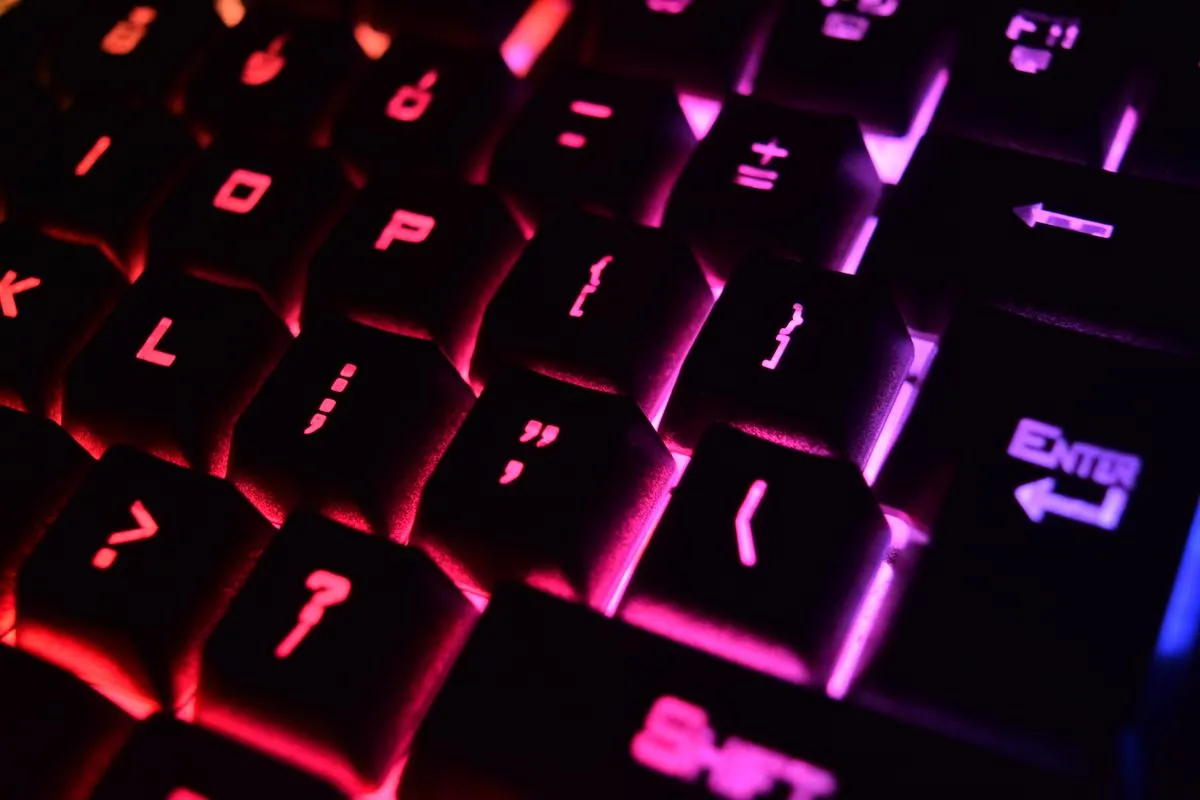 赤い光を受けた黒いキーキャップの列に、句読点や記号のバックライトが浮かんでいる
