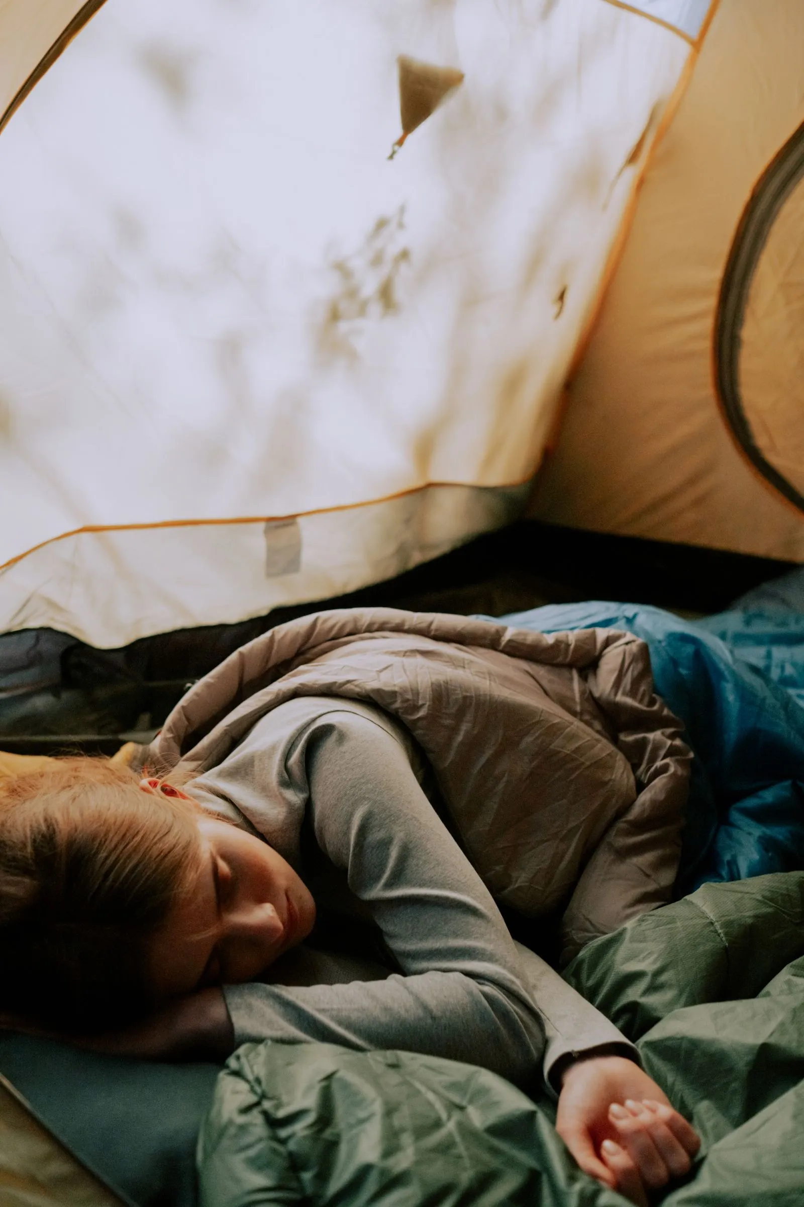 テントの中で寝袋にくるまって眠る人物