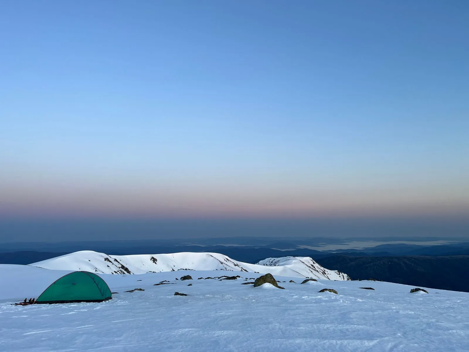 雪山の頂上に夕暮れどき、ぽつんと立つテント