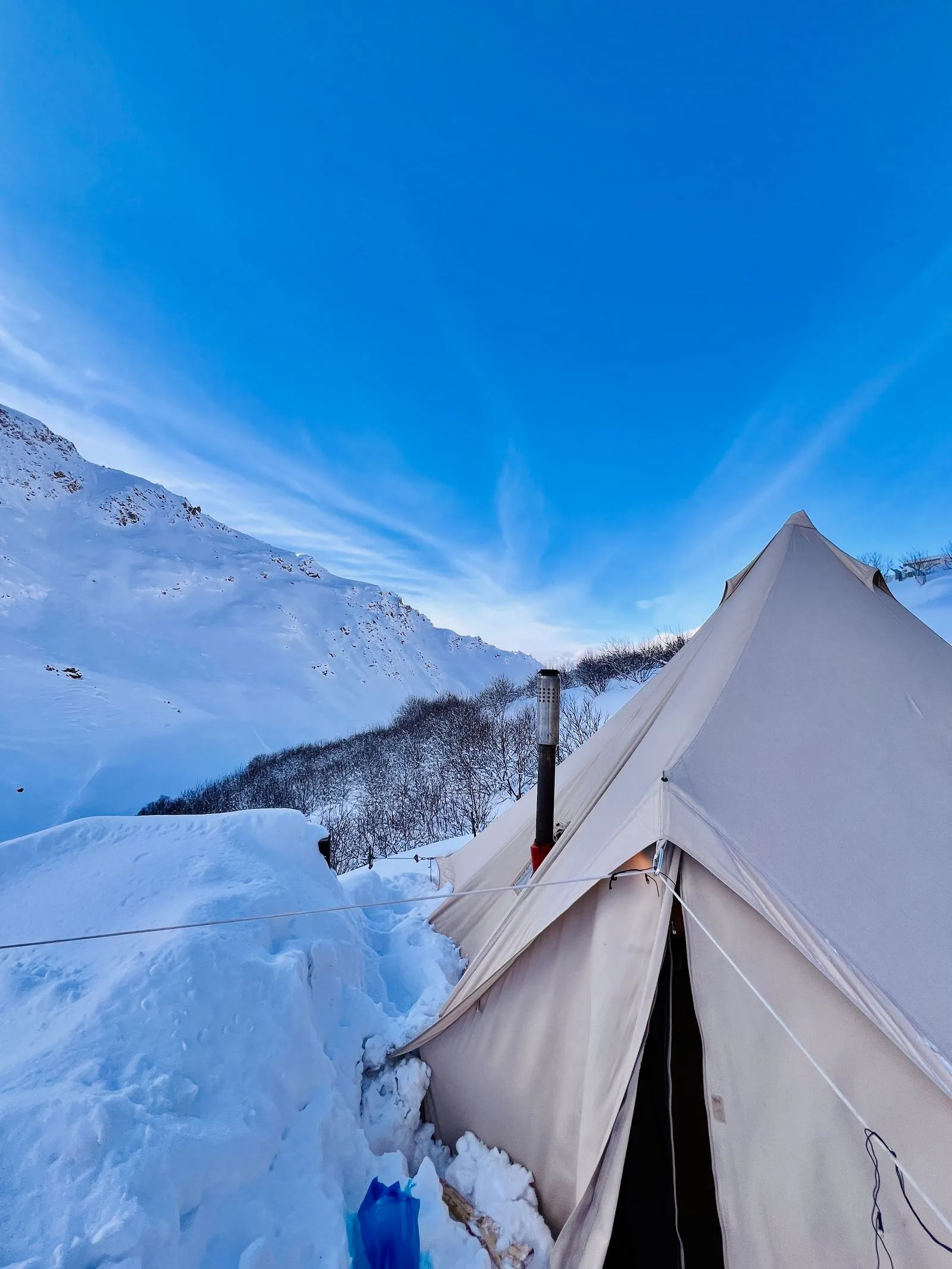 雪山にキャンバス地のベルテントが張られている風景