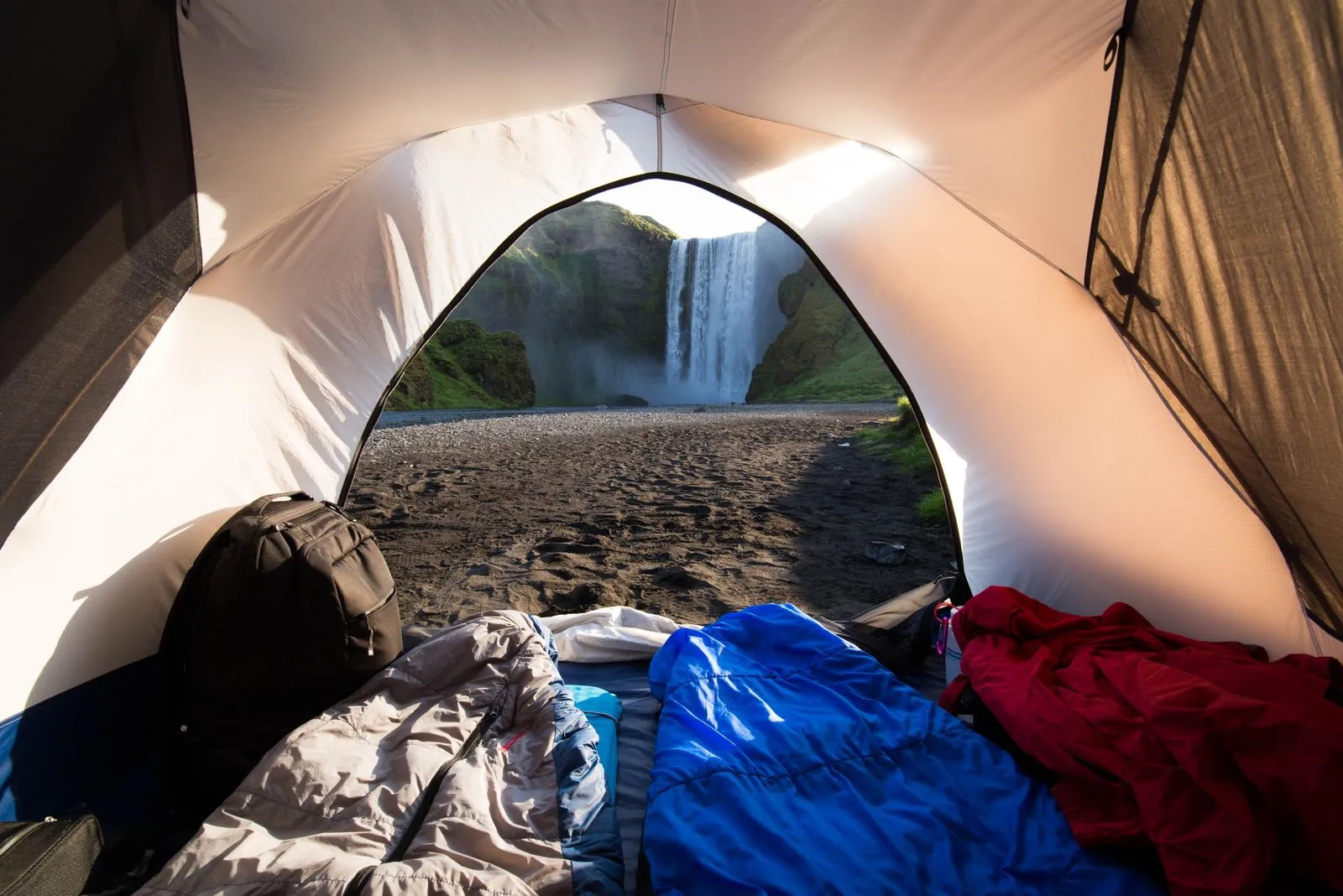 テントの中から見える滝のある山の景色