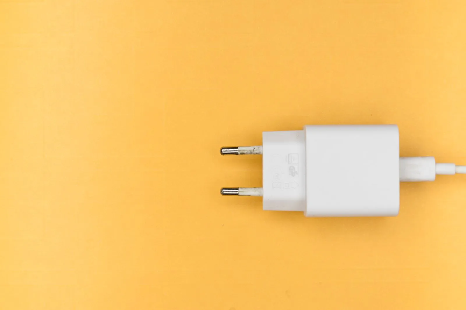黄色い背景に置かれた白い電源プラグ