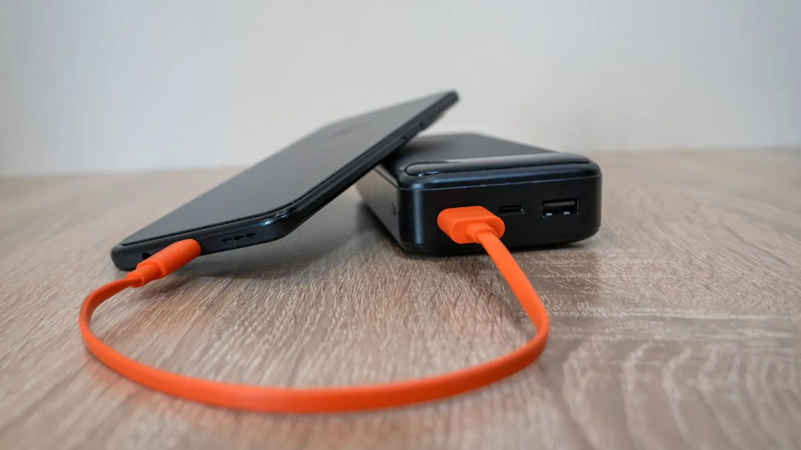 オレンジ色のケーブルでスマートフォンと充電器がつながる様子