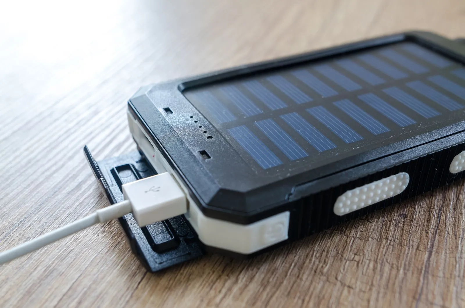 木の板の上でUSBケーブルにつながるソーラー充電器