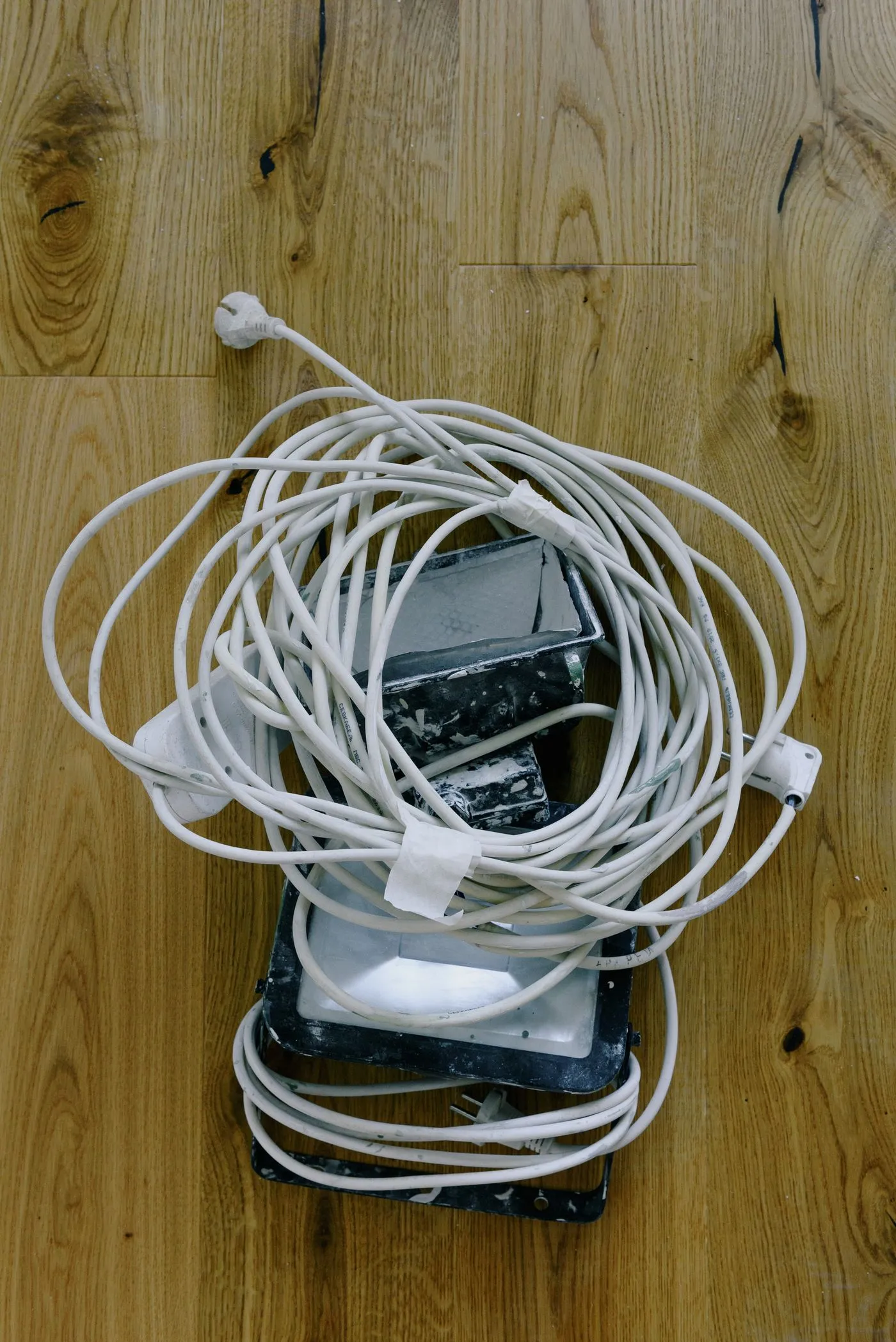 木の床の上にまとめて置かれた白い電源コードと電源タップ