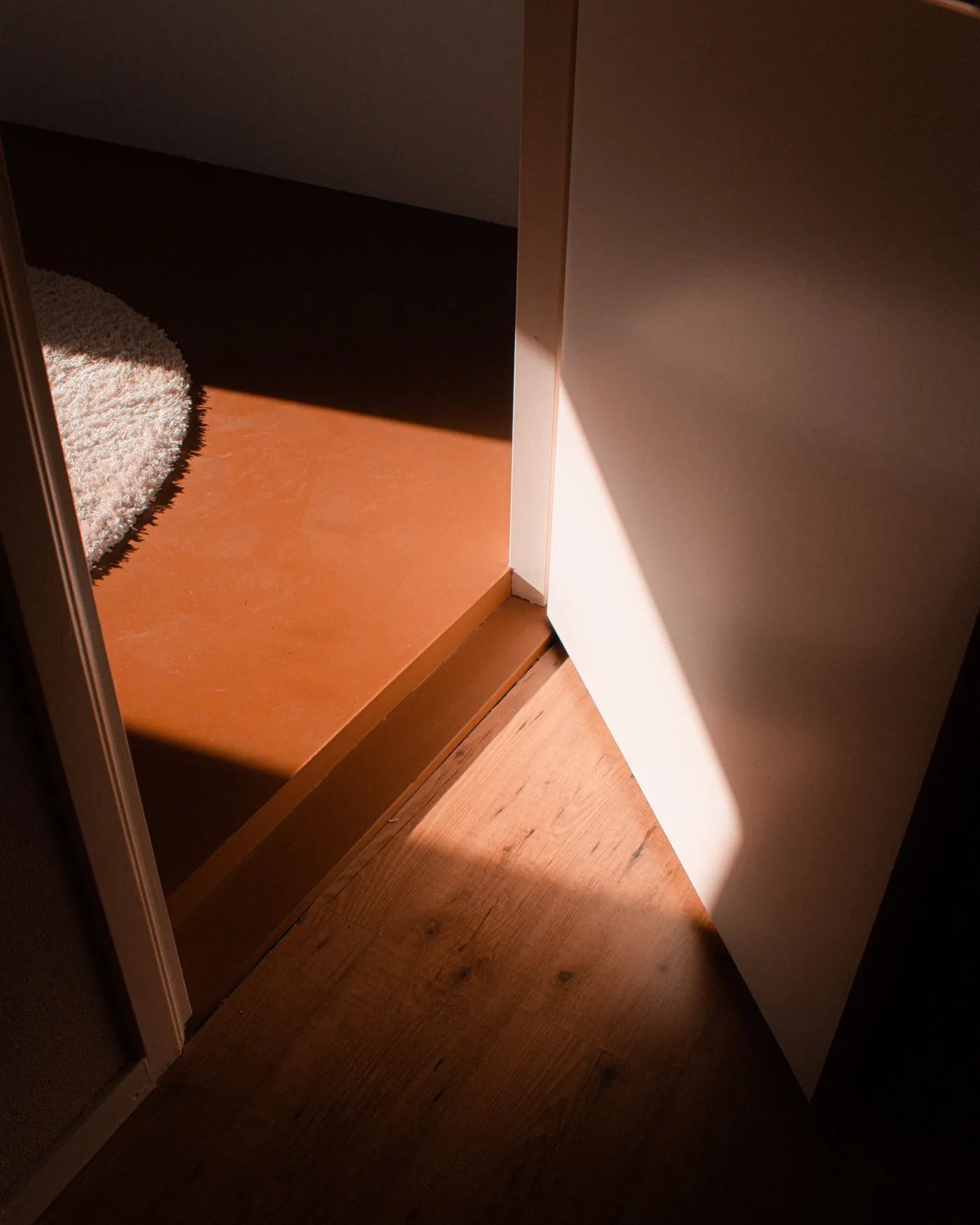 開いた扉の下に見える床の敷居と、差し込む光