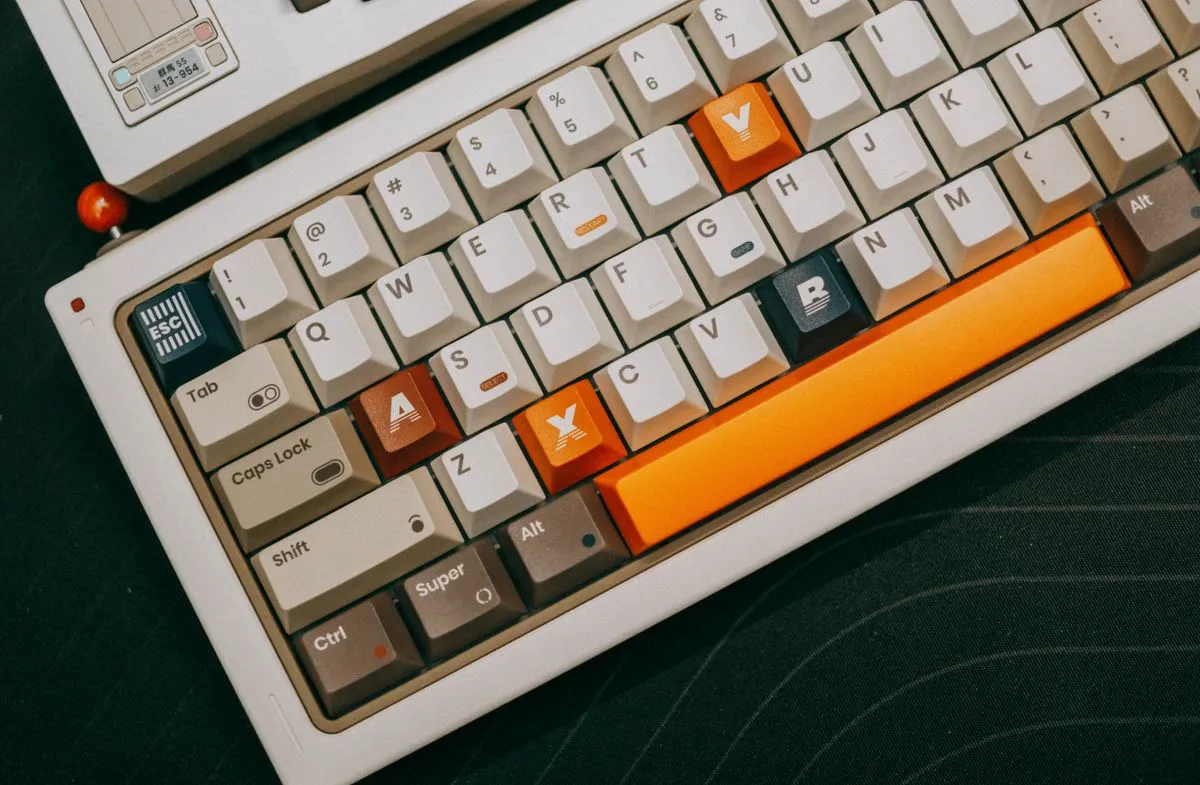 オレンジ色のキーキャップが並ぶキーボードの端に、小さなオレンジのボールチェーンが掛かっている