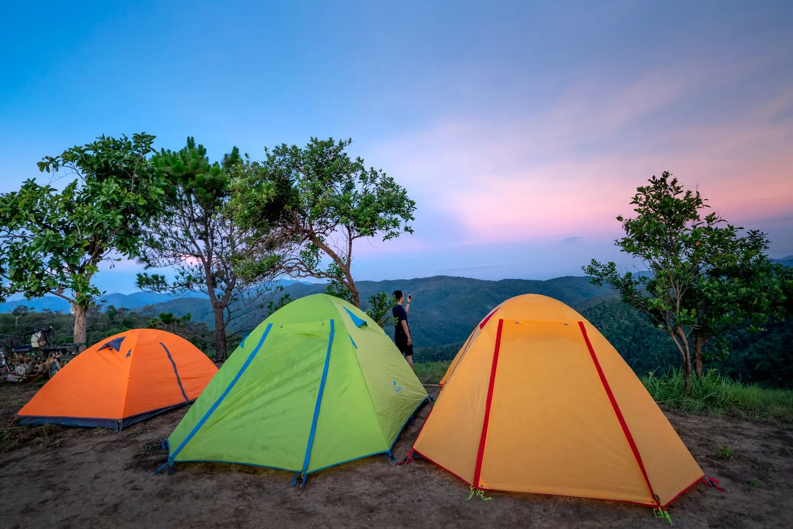 夕暮れの山でオレンジ・緑・黄色のドーム型テント3張り