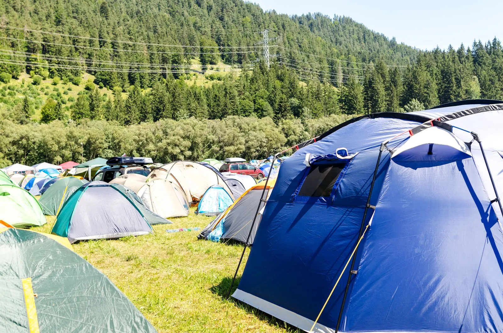 山を背景にした緑の広場に並ぶ色とりどりのテント